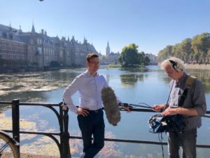 Interview met een persoon, waarbij het Binnenhof op de achtergrond te zien is.