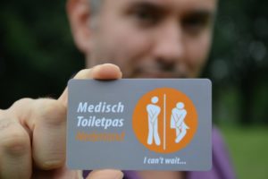 Persoon met pasje van Medisch Toilet Nederland in zijn hand